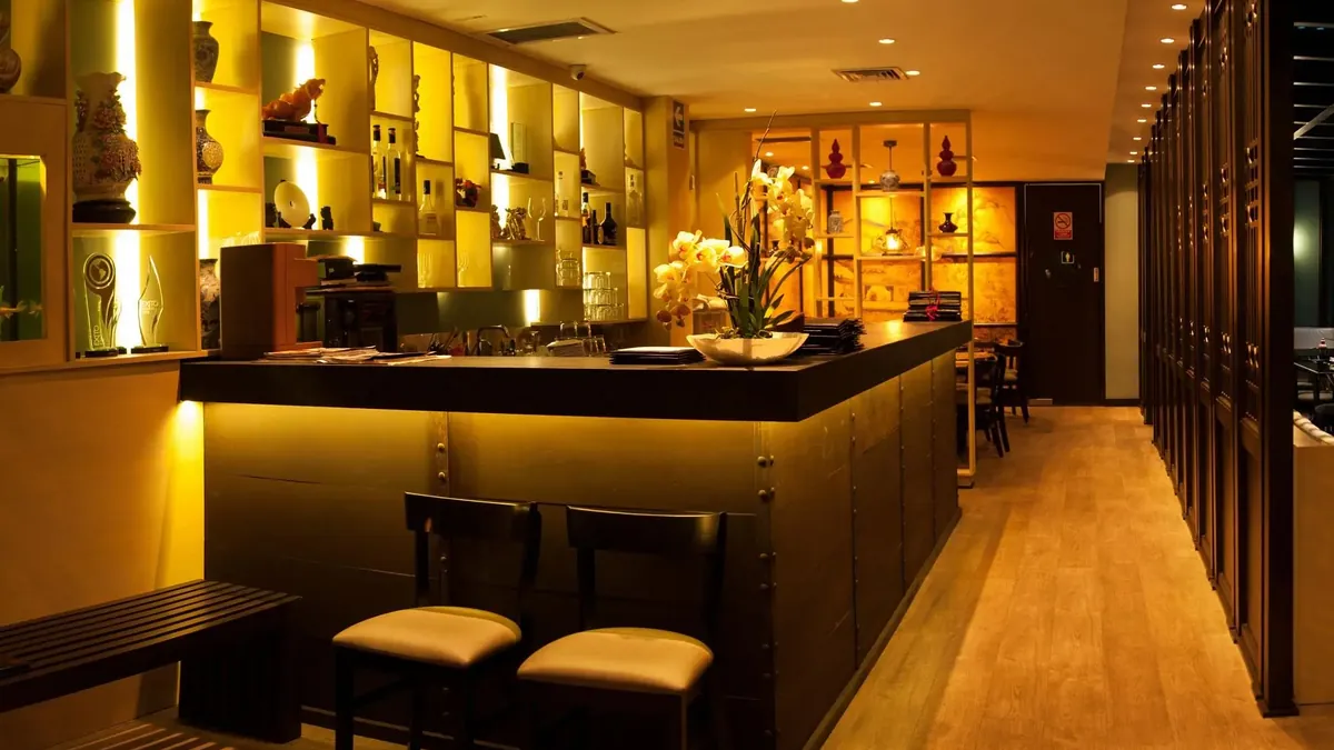Barra de un restaurante en San Isidro con iluminación cálida y estanterías decoradas