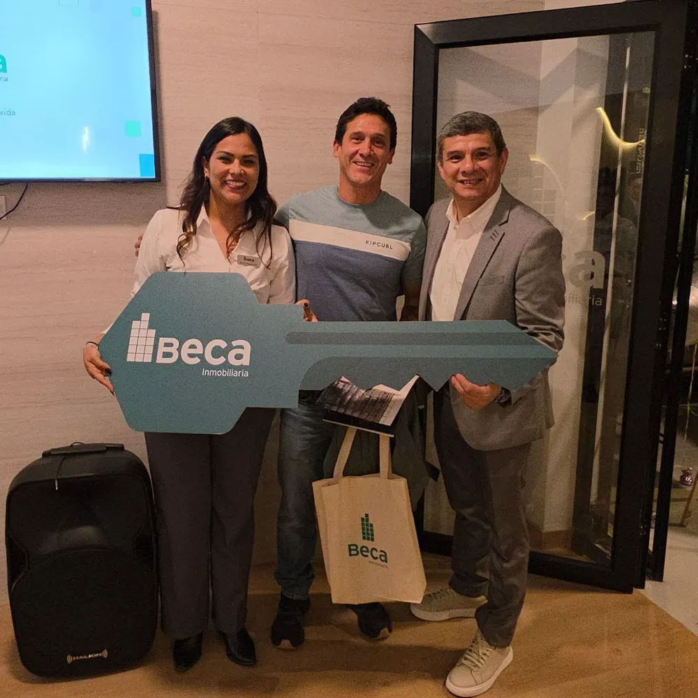 Entrega de llaves de BECA Inmobiliaria: un propietario sostiene la llave gigante de la marca junto a dos miembros del equipo